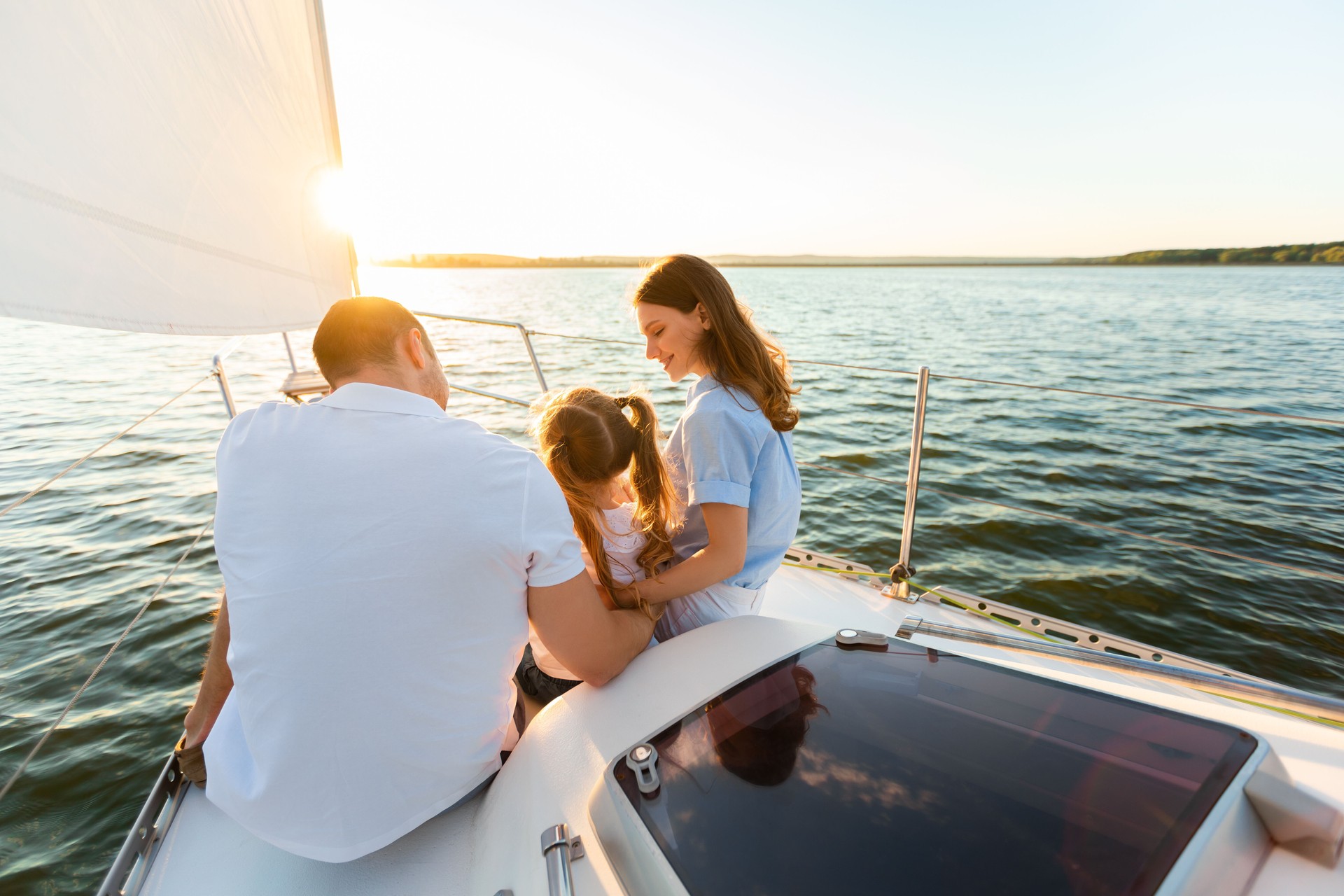 Famiglia seduta a poppa di uno yacht mentre naviga lungo la costa